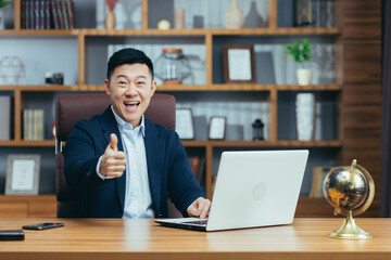 Wall Mural - Portrait of a successful asian politician lawyer, man working at desk in classic office, looking at camera and smiling