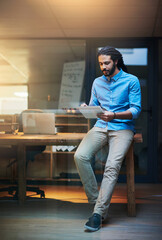 Fototapete - Browsing around for some ideas online. Shot of a young designer working late on a digital tablet in an office.