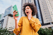© Jose Calsina - Cute girl holding smart phone in hand, surprised young woman watching cell