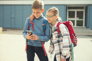 Wall Mural - Teen schoolchildren playing with cell phone in school yard