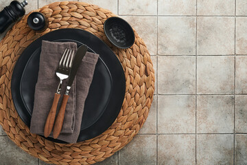 Wall Mural - Ceramic empty black plate, silverware and linen kitchen towel napkin on old ceramic tile table background. Cooking stone backdrop. Top view with copy space. Flat lay