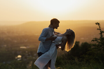 Happy young couple spend time outdoors at sunset. Man and woman on a romantic date at sunset picnic. Picnic for lovers. 