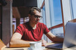 © DSMT - Smart software developer sitting at desktop in coworking space with laptop and creating publishing idea, using netbook for messaging and networking during freelance work