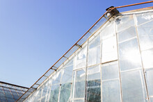 Old Destroyed Greenhouse With Broken Window Glasses And Rusty Frame. Urban Ruined Geometry. Blue Sky.