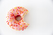 Closeup of a bitten pink glazed donut isolated on a white background with copy space