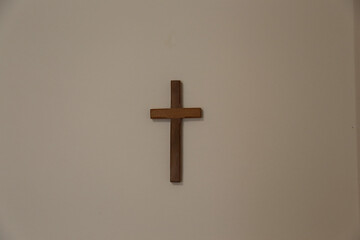 Wooden simple cross on a white wall in the room