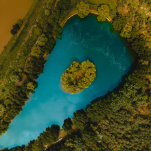 Aerial Shot Of A Blue Lake With Small Island In The Middle And Trees Around