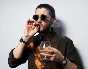 Portrait of young man with a cigar and whiskey on white background.