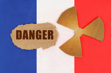 On the flag of France, the symbol of radioactivity and torn cardboard with the inscription - Danger