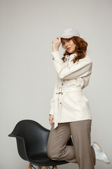 A model in a brown dress suit on a studio background. The girl next to the chair. Shooting fashion clothes