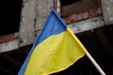 National Flag Of Ukraine In Front Of Abandoned Destroyed House Building. Blue And Yellow Ukrainian Banner On Bomb Destruction Ruined Site.