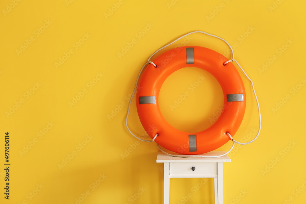 Ring buoy on table near yellow wall