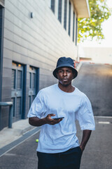 Black man posing with a mobile phone in the streets