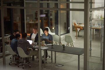 Poster - Putting in some extra hours at work. Shot of employees working in an office at night.