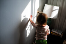 Toddler Leans On Wall With Shadow