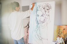 Woman Paints A Large Canvas Portrait.