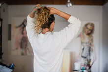 Woman Fixes Her Hair In Her Painting Studio.
