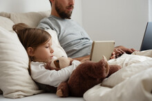 Bored Daughter Browsing Tablet Near Working Father