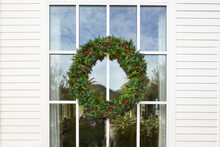 Green Christmas Wreath On Resort Window With Red Berries