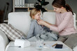 © Sergey Narevskih/Stocksy - Woman doing inhalation to sick child sitting on sofa