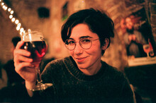 Young Woman With Short Dark Hair Drink Beer In Cave Style Belgium Bar