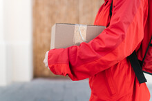 Faceless Delivery Worker Walking On Street With Parcel