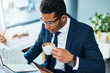 © K Seisa/peopleimages.com - His daily schedule is always full. Shot of a focused young businessman seated at his desk while drinking coffee and reading his journal in the office.