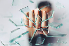 Close Up Of A Man's Fist Punching And Breaking Glass To Pieces - Home Security Concept - Business Challenge