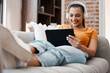 © Micah C/peopleimages.com - Catching up on my favourite show. Shot of a young woman relaxing while using a digital tablet at home.