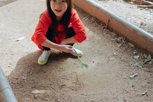 Child Draws On The Ground With Twig