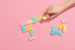 © Marc Tran/Stocksy - Girl plays dominoes. Domino closeup on a pink table background.