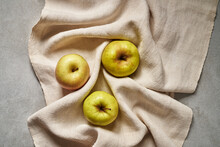 Three Yellow Apples On A Linen