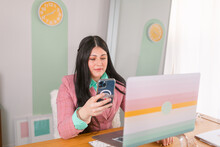 Young Businesswoman Using Phone In Colorful Workplace