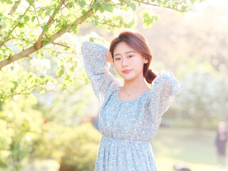 Portrait of elegant Chinese girl in dress enjoy carefree time in forest park in sunny day. Outdoor fashion portrait of glamour young Chinese cheerful stylish woman.