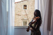 © Gabriel (Gabi) Bucataru/Stocksy - Black girl with viola by an open window