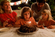 A Girl Blowing Candles On The Cake In The Garden