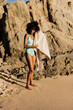 © Marc Bordons/Stocksy - Young woman dries her hair on the shore of the beach
