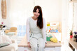 © Albert Martinez/Stocksy - Positive lady sitting on table near knitting tools