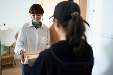 Happy Female Receiving Parcel From Courier