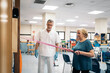© Santi Nuñez/Stocksy - Aged patient exercising with elastic band near doctor