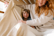 A Little Boy Is Hiding Under A Blanket