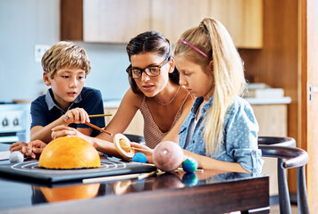 Poster - Learning all about outer space. Shot of a mother helping her two young children with a school project at home.