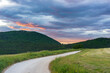 Sunset dramatic sky over country road in Marche region, Italy. Epic clouds above winding trail unique hills and mountains landscape, emotional feeling concept.