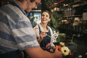 Flowers brighten up any day. Cropped shot of two young florists working together inside their plant nursery.