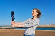© Valerii Honcharuk - Middle-aged woman recording video on smartphone with outdoor on seashore