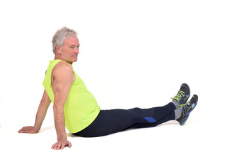 Poster - side view of a senior man with sportswear stiitng on the floor looking away on white background