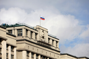 Wall Mural - Russian flag on the parliament building in Moscow on background of blue sky and white clouds, authorities of Russia