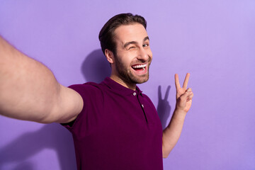 Wall Mural - Photo of impressed millennial brunet guy do selfie blink wear violet t-shirt isolated on purple color background