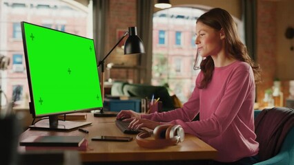 Poster - Young Pretty Female Working from Home on Desktop Computer with Green Screen Mock Up Display. Creative Woman Checking Social Media, Browsing Internet. Loft Apartment with City View from Big Window.
