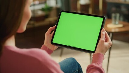 Fototapete - Female Holding Tablet Computer with Green Screen Mock Up Display. Woman Relaxing at Home, Watching Videos and Reading Social Media Posts on Mobile Device. Close Up Over the Shoulder Footage.